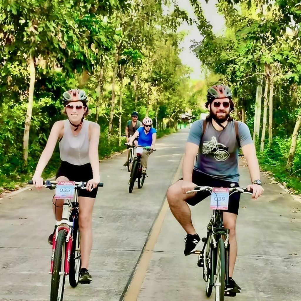 Cyclists riding along a quiet tree-lined road in Bang Krachao