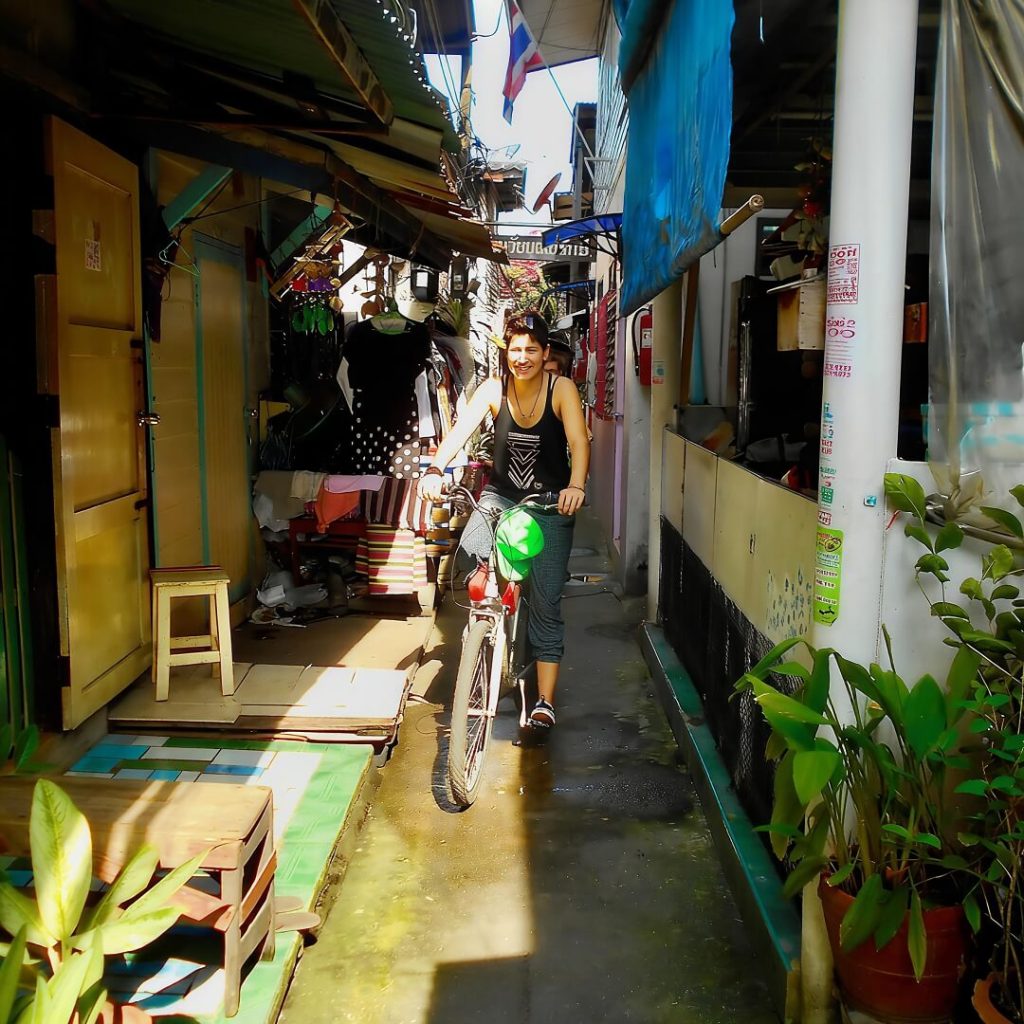 Cyclists riding through a narrow village lane in Bang Krachao