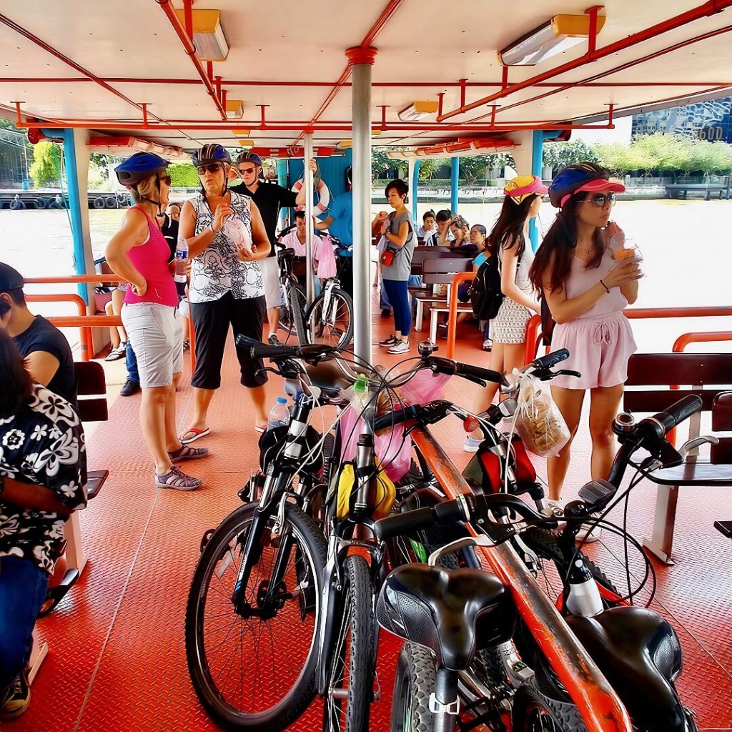 Guests standing with their bicycles on a river ferry crossing the Chao Phraya River in Bangkok