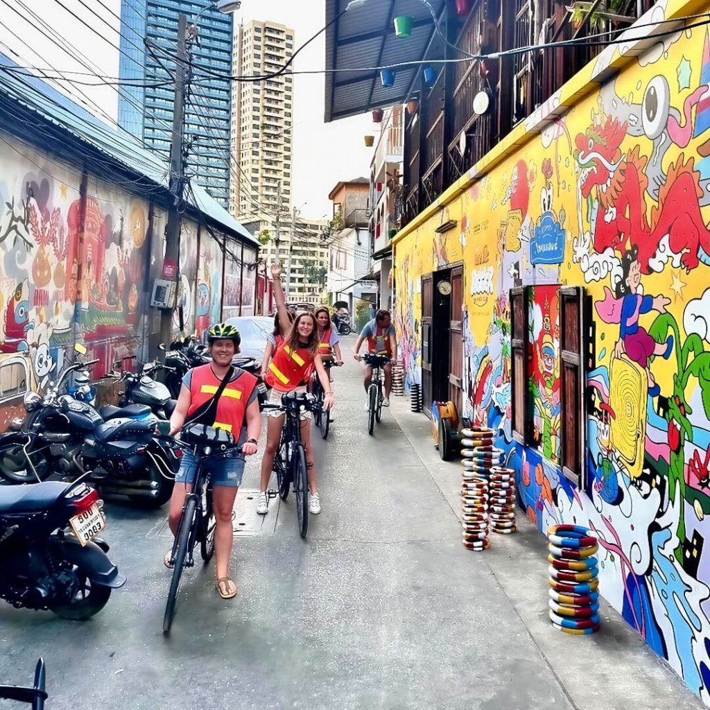 Cyclists riding through Talat Noi in Bangkok