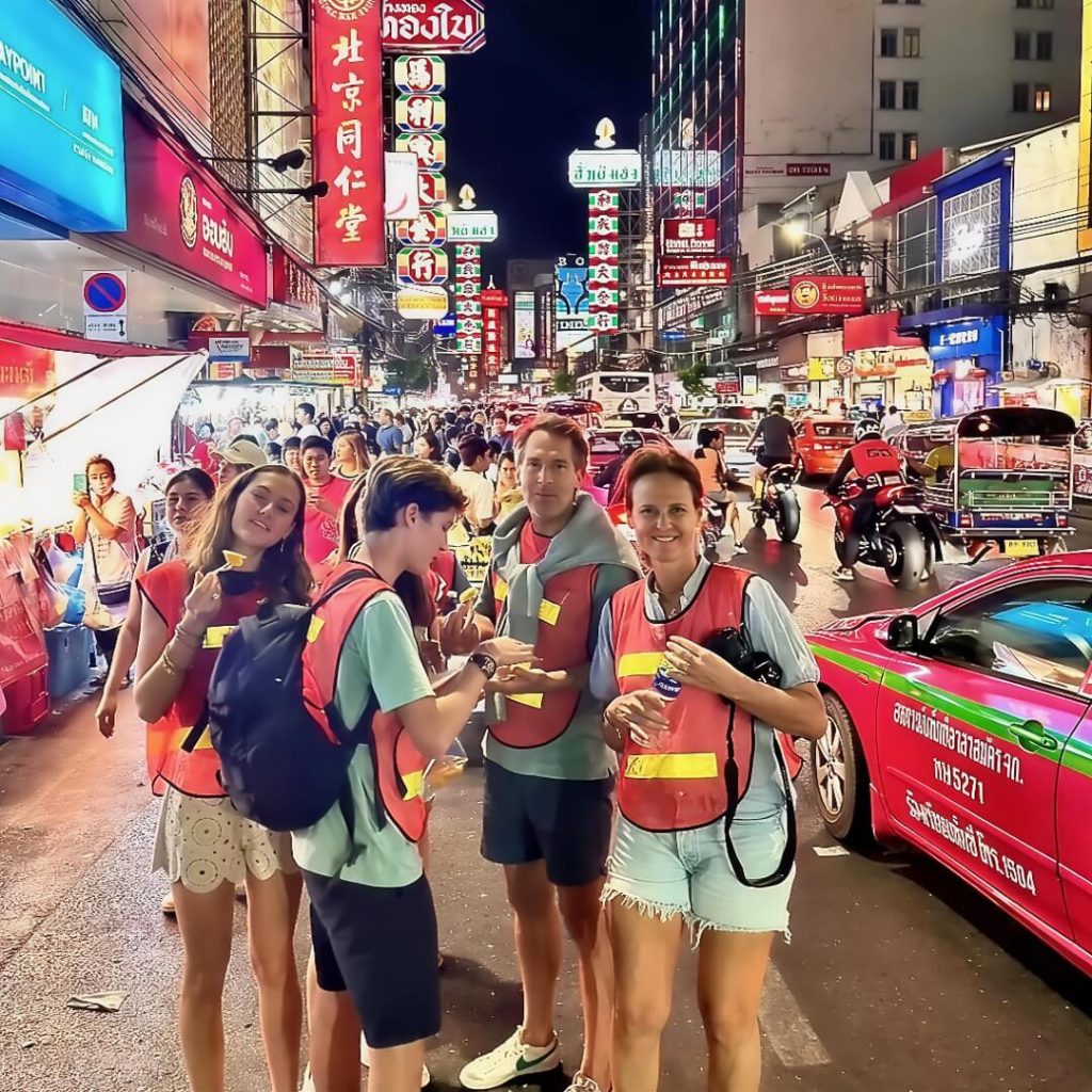 Cyclists standing on Yaowarat Road in Chinatown at night