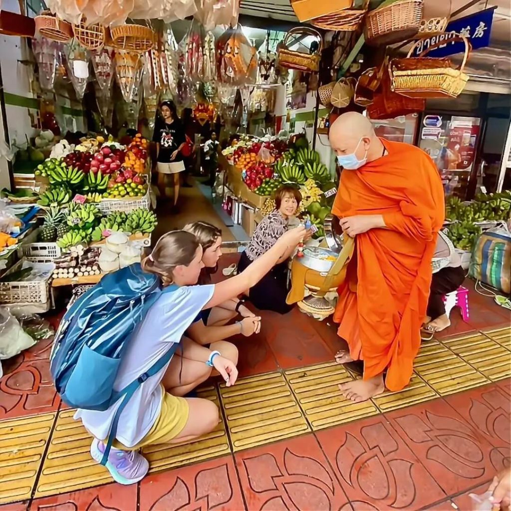 Guests kneeling while making an offering to a Buddhist monk in Bangkok