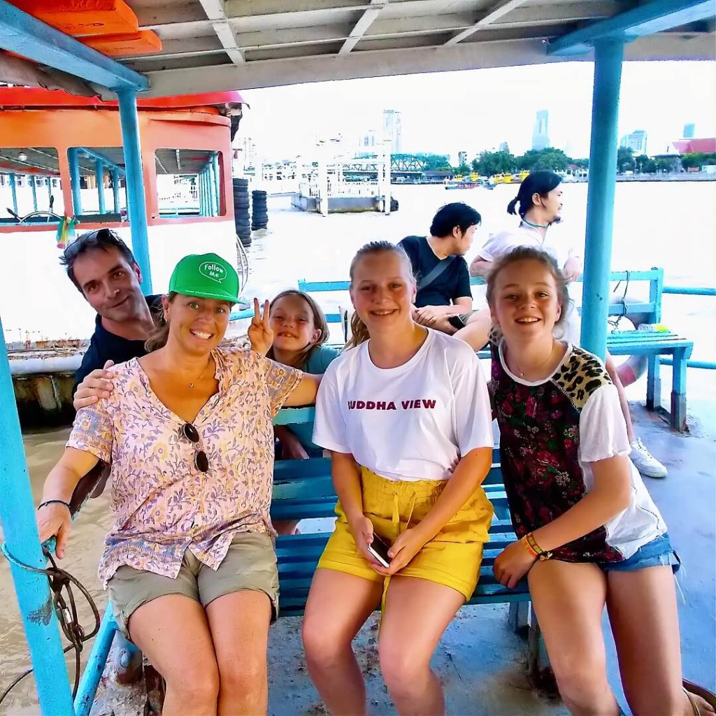 Guests on a local river ferry crossing the Chao Phraya River with Memorial Bridge in the background