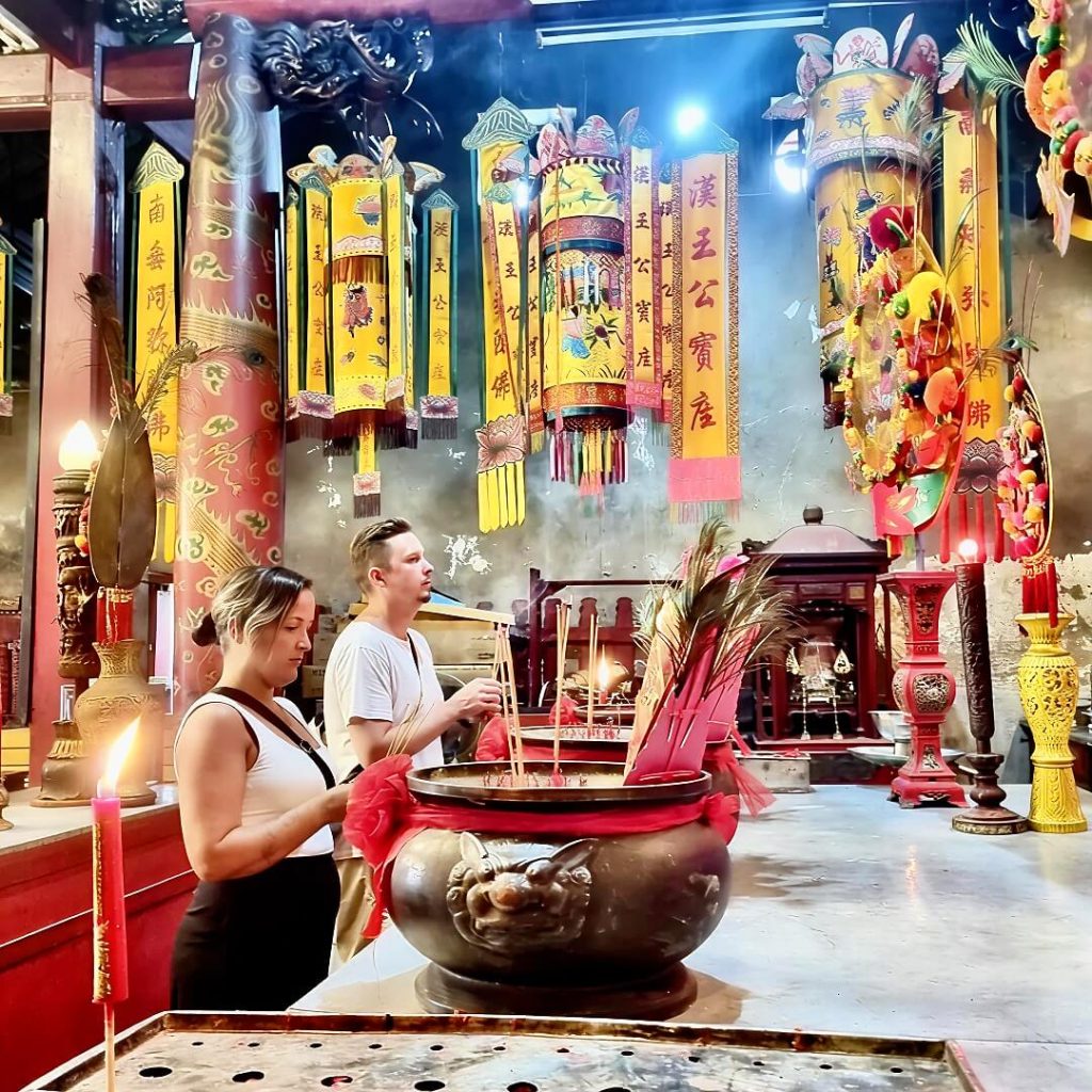 Guests making an incense offering inside a Chinese shrine in Bangkok