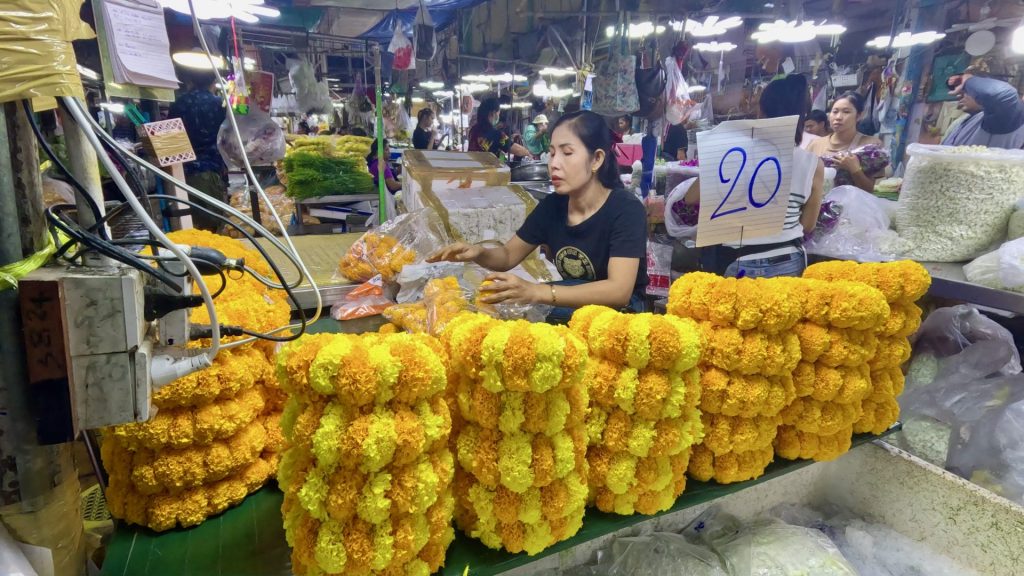 A market vendor making Marigold garlands in Pak Khlong Talat