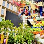Split view of Silom in Bangkok with office tower on one side and street market vendors on the other during a walk from Sala Daeng to Chong Nonsi BTS