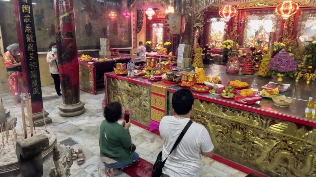 Person shaking a container of fortune sticks during the Kau Cim ritual at San Chao Pho Suea, seeking guidance in love, health, and business.
