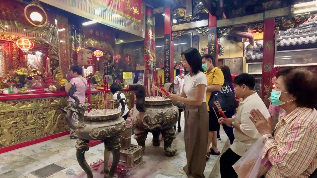 Worshippers burning incense sticks before the Tiger God statue inside San Chao Pho Suea shrine.