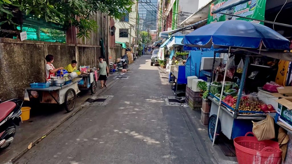 Quiet alley near Wat Hua Lamphong with local street vendors preparing food on a Saturday morning in Bangkok.