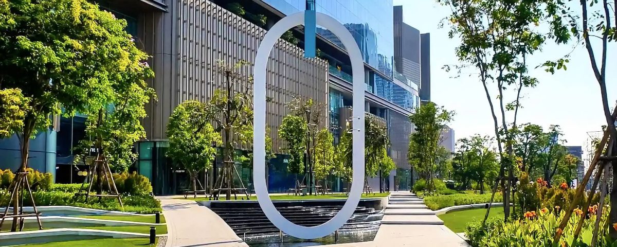 Cycling around One Bangkok with modern architecture, landscaped gardens, water features and the O landmark in the foreground