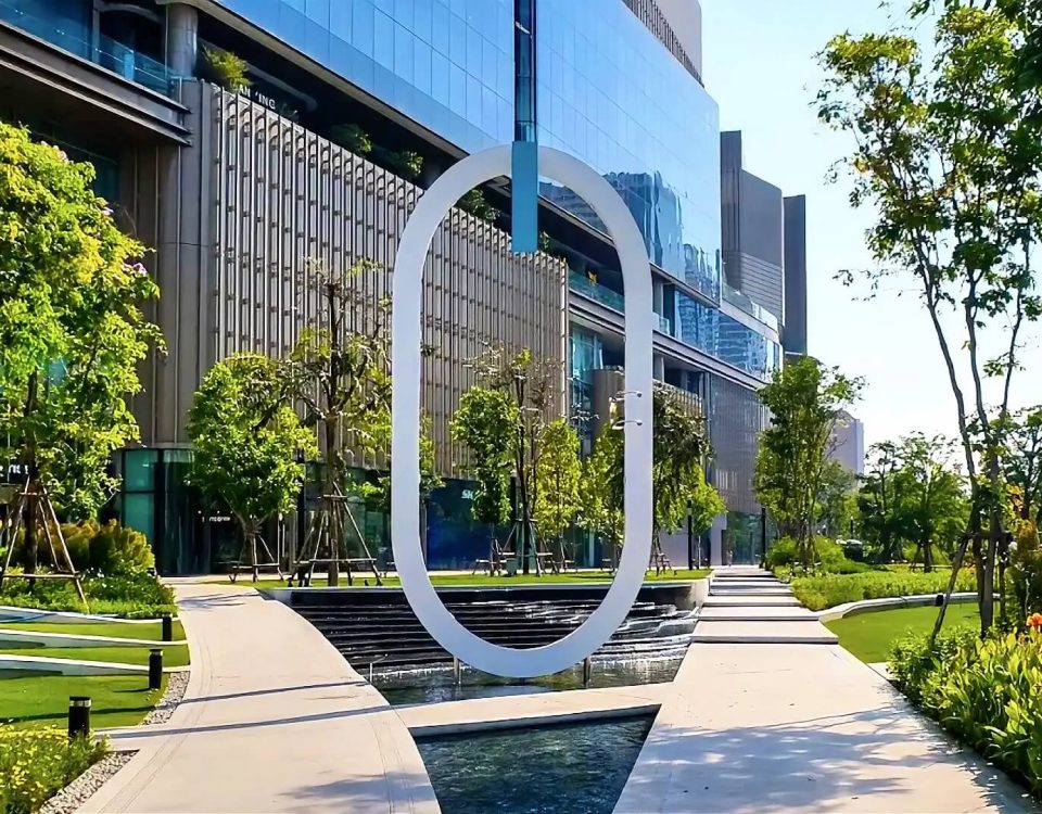 Cycling around One Bangkok with modern architecture, landscaped gardens, water features and the O landmark in the foreground