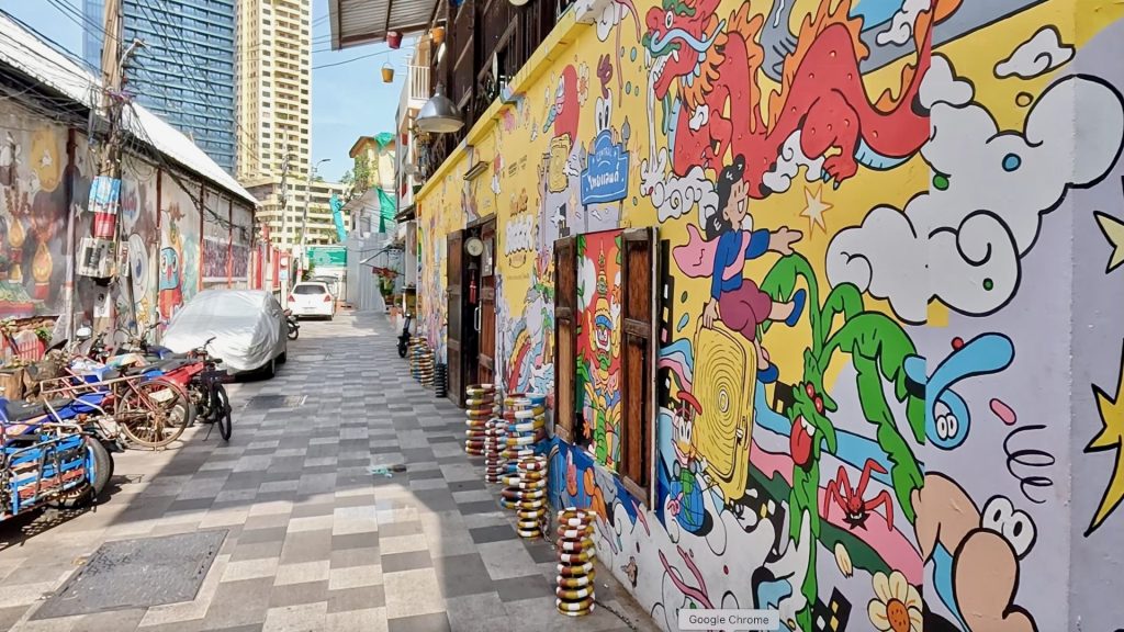 Early Saturday morning view of Talat Noi alley with colourful yellow street art murals and historic shophouses in Bangkok.