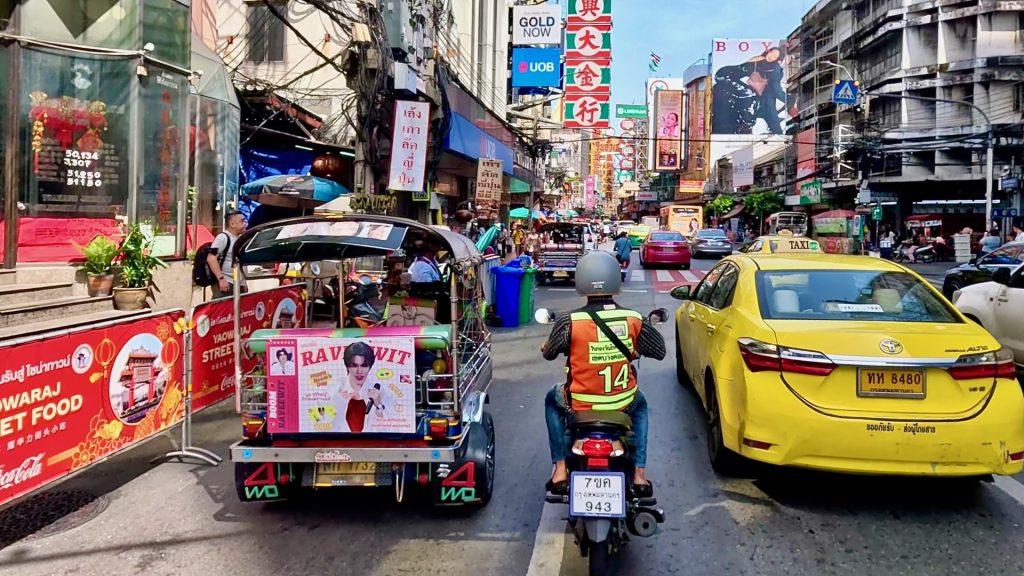 Yaowarat Road in Bangkok’s Chinatown on a Saturday morning with taxis, tuk tuks, colourful signs, and early shoppers.