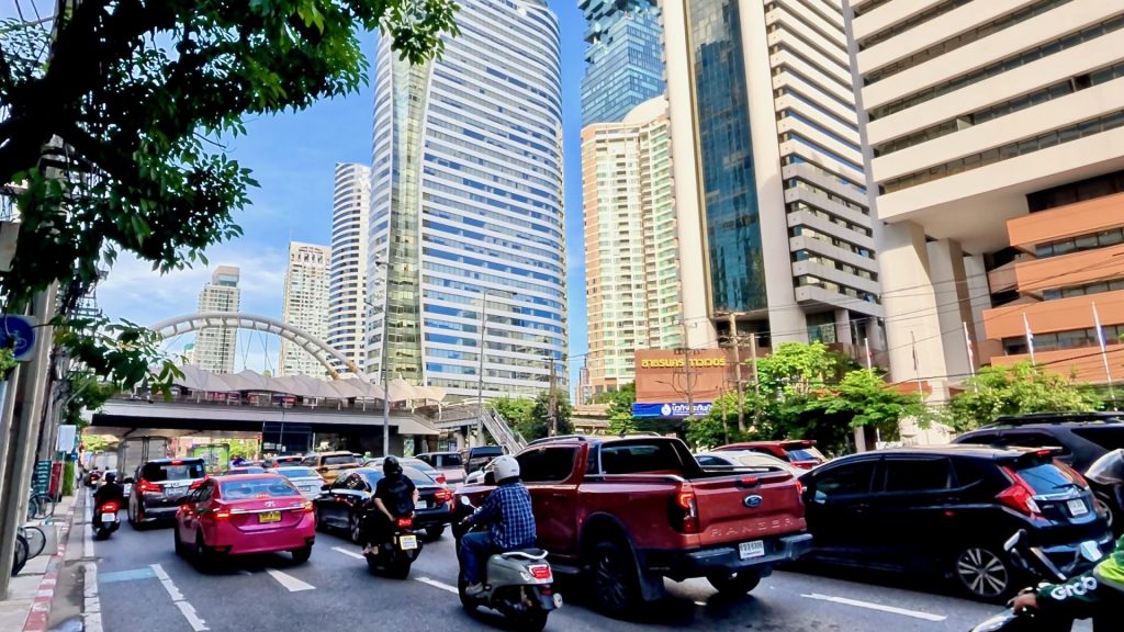 Iconic view of Chong Nonsi Skywalk surrounded by modern office towers, busy traffic, and a clear blue Bangkok sky — a landmark of the city’s financial district.