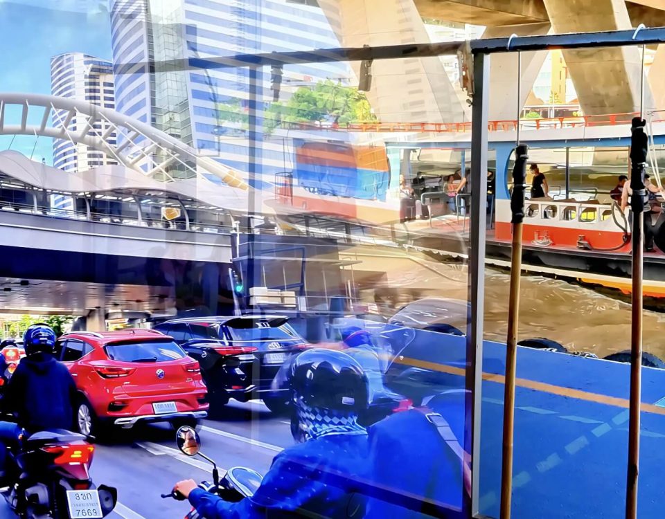 Cycling from Chong Nonsi Skywalk to Sathon Pier showing traffic under the skywalk and a ferry approaching the pier on the Chao Phraya River in Bangkok