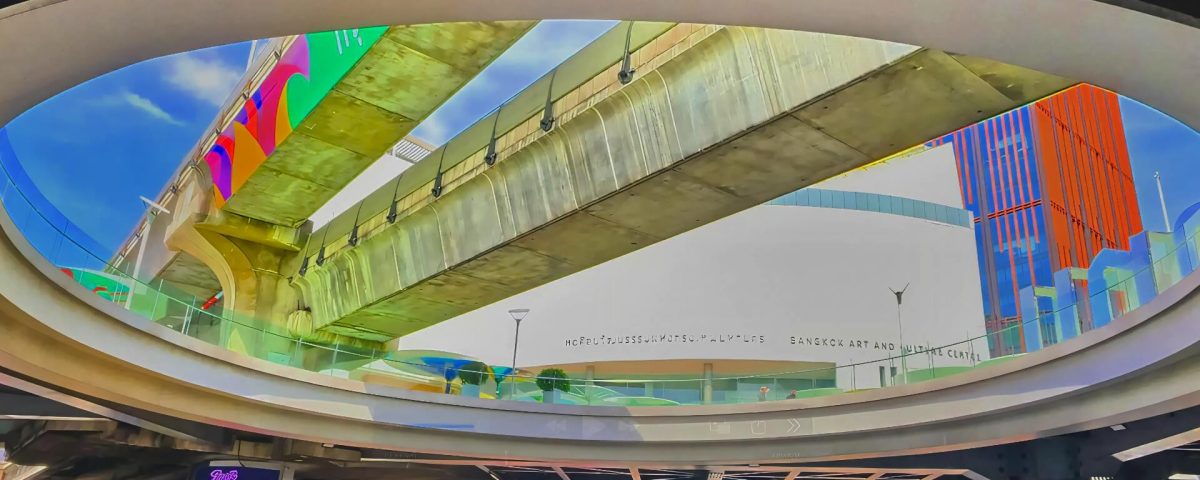 Cycling from Siam Paragon to MBK Center showing walkway view looking up to BTS Skytrain tracks above MBK in Bangkok