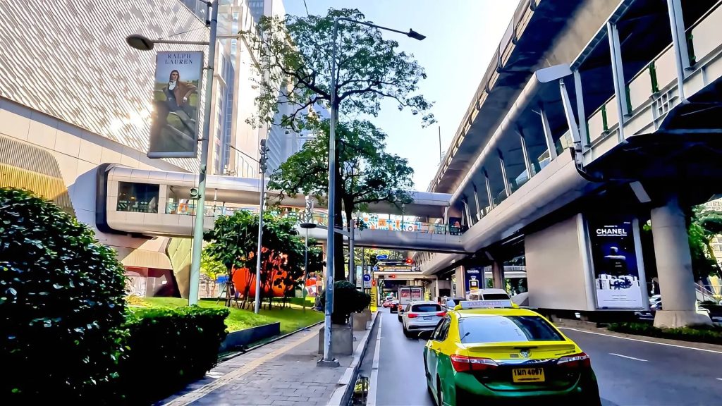 Cycling from Gaysorn Centre to Nana BTS showing Sukhumvit Road with shopping complex, BTS Skytrain and busy traffic in Bangkok