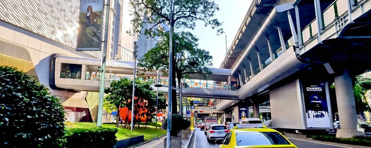 Cycling from Gaysorn Centre to Nana BTS showing Sukhumvit Road with shopping complex, BTS Skytrain and busy traffic in Bangkok