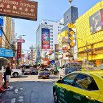 Busy traffic along Yaowarat Road in Bangkok Chinatown with colourful shop signs and buildings