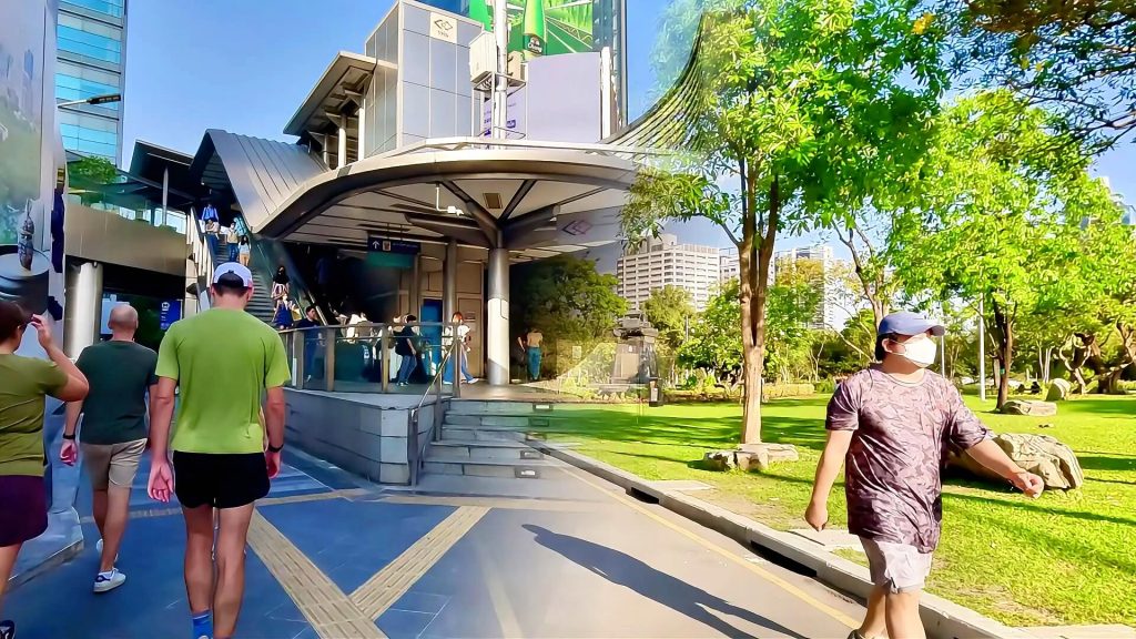 Si Lom rush hour commuters at MRT station contrasted with quiet Lumphini Park walking path Bangkok