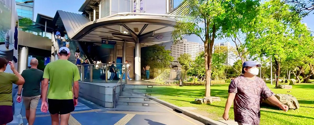 Si Lom rush hour commuters at MRT station contrasted with quiet Lumphini Park walking path Bangkok