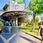 Si Lom rush hour commuters at MRT station contrasted with quiet Lumphini Park walking path Bangkok