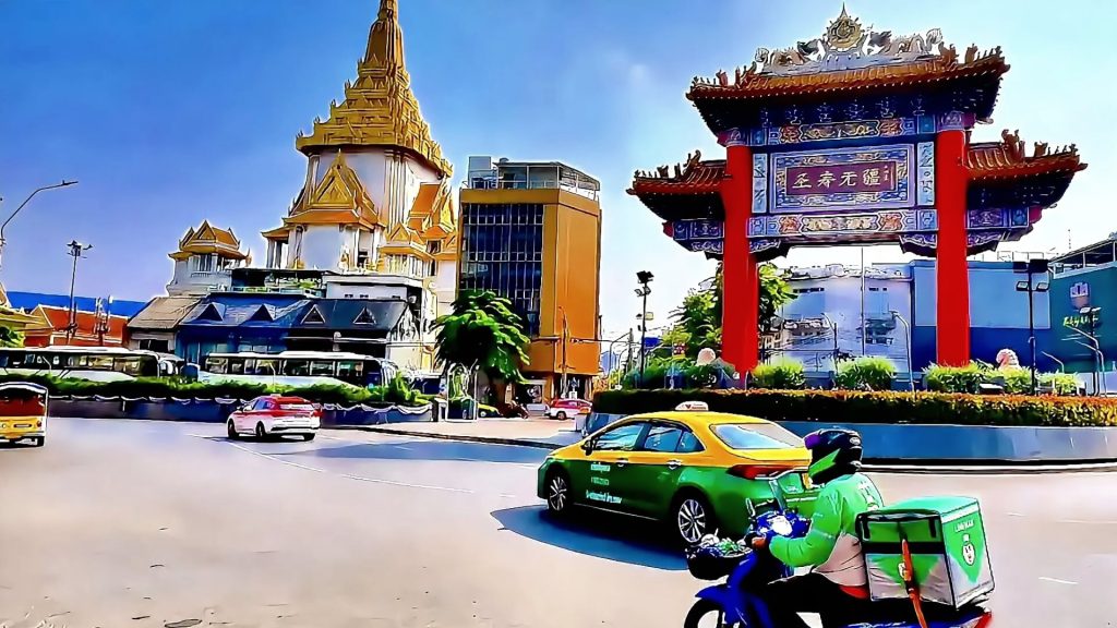 Chinatown Gate on Yaowarat Road Bangkok with light traffic and temple in background
