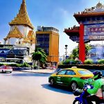 Chinatown Gate on Yaowarat Road Bangkok with light traffic and temple in background