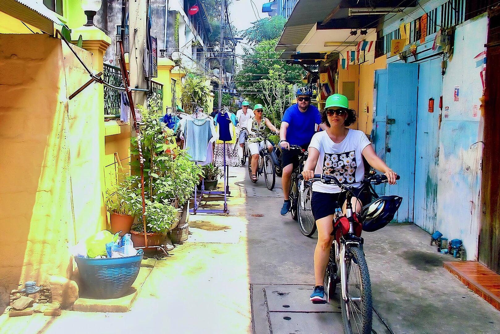 Guests cycling through a narrow neighbourhood street in Bangkok