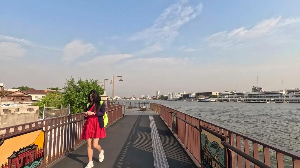Pedestrian walking along the Chao Phraya riverside walkway in Bangkok