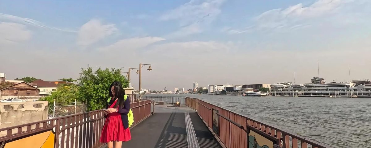 Pedestrian walking along the Chao Phraya riverside walkway in Bangkok