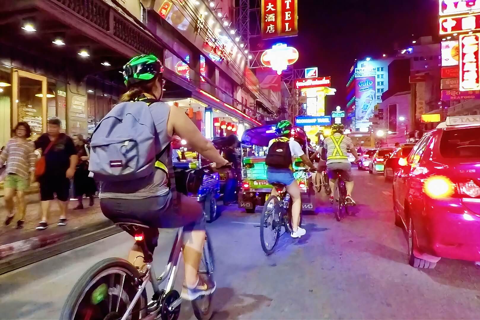 Cyclists riding along Yaowarat Road in Chinatown at night in Bangkok