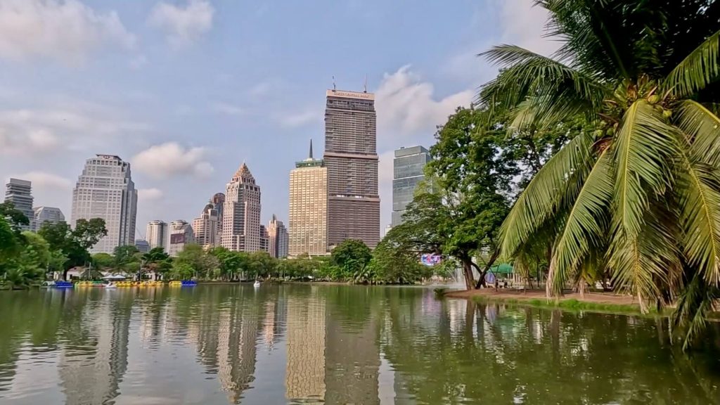 View across Lumphini Park lake with Bangkok skyline in the background