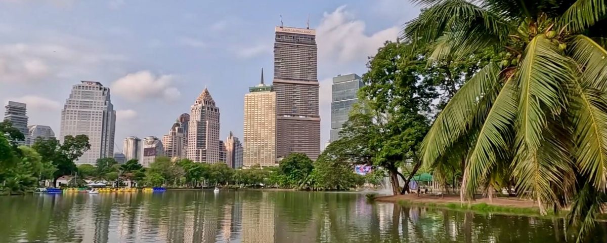 View across Lumphini Park lake with Bangkok skyline in the background
