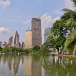 View across Lumphini Park lake with Bangkok skyline in the background