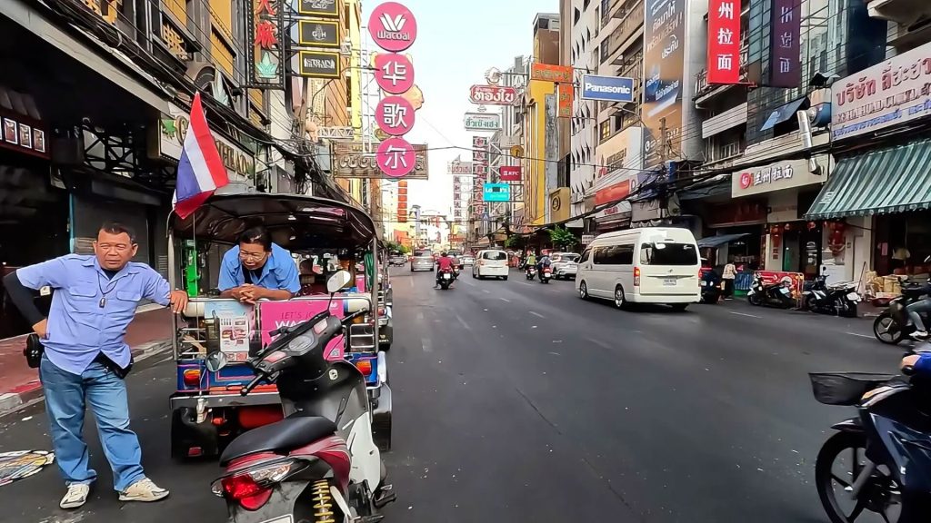 Yaowarat Road in Bangkok with morning traffic and shop signage as activity increases