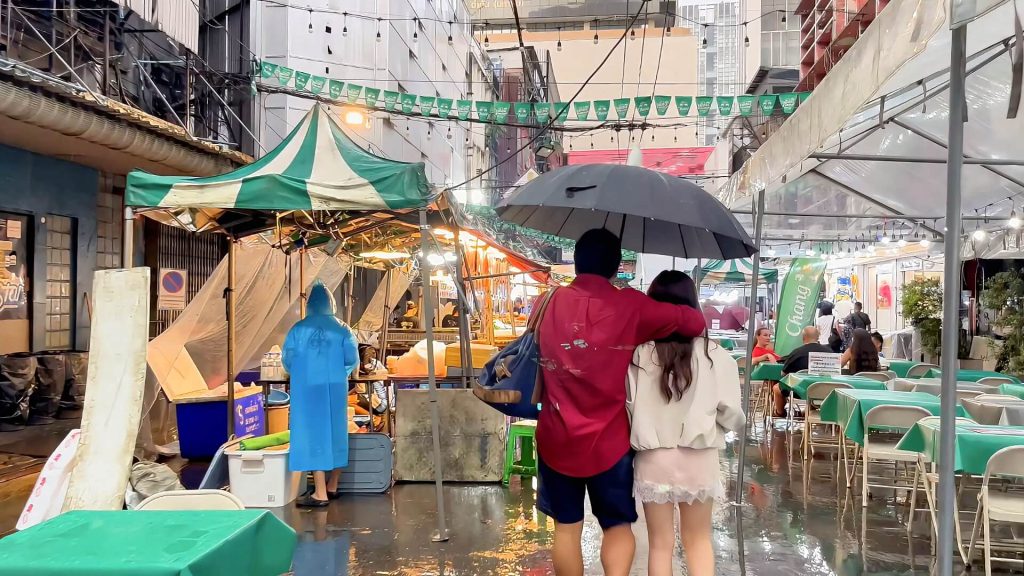 Evening activity in Patpong during heavy rain as markets prepare to open.