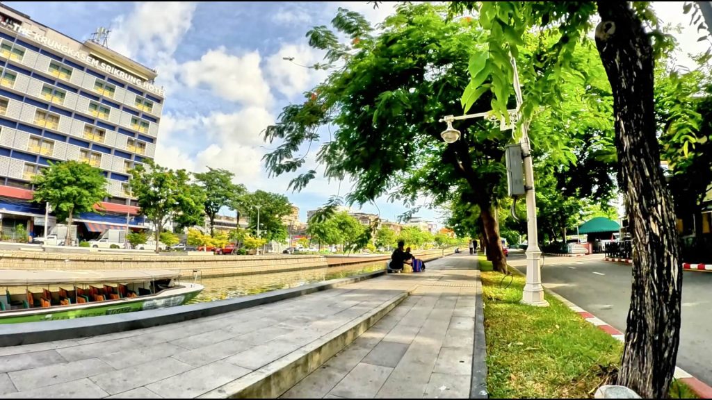 Cycling beside Phadung Krung Kasem Canal with canal boats and shared pathways in Bangkok.