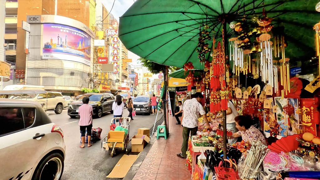 Busy Yaowarat Road with traffic, shops and colourful signage in Bangkok's Chinatown.